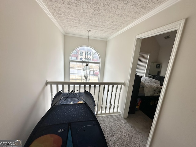 hallway with ornamental molding, carpet flooring, and a textured ceiling