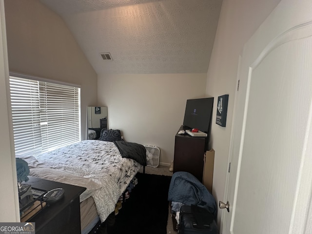 carpeted bedroom with vaulted ceiling and a textured ceiling