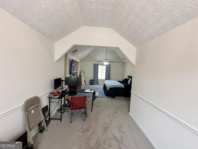 bedroom with vaulted ceiling, light colored carpet, ceiling fan, and a textured ceiling