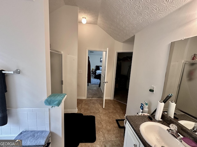 bathroom featuring vanity, vaulted ceiling, a textured ceiling, and a shower with shower door