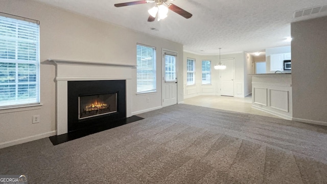 unfurnished living room featuring carpet floors, a textured ceiling, and ceiling fan