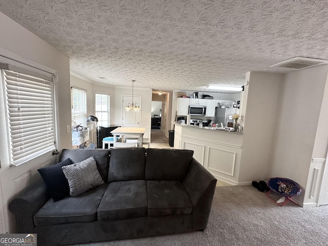 living room with an inviting chandelier, crown molding, light carpet, and a textured ceiling