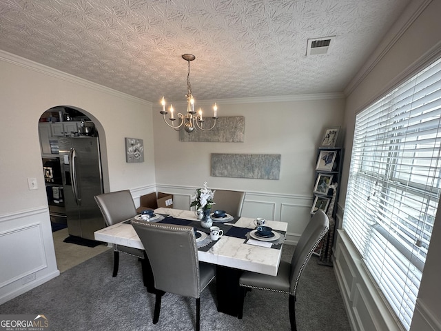 carpeted dining space with crown molding, a chandelier, and a textured ceiling