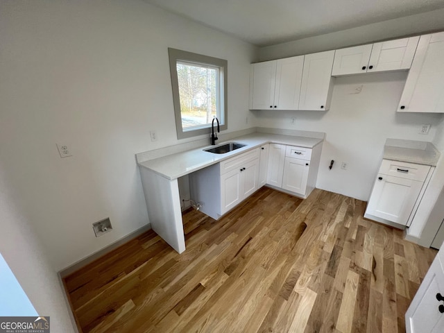 kitchen with sink, white cabinets, and light hardwood / wood-style flooring