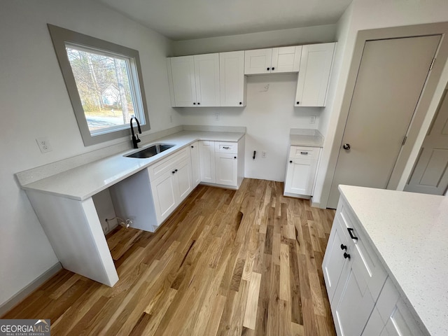 kitchen with light wood-type flooring, sink, and white cabinets