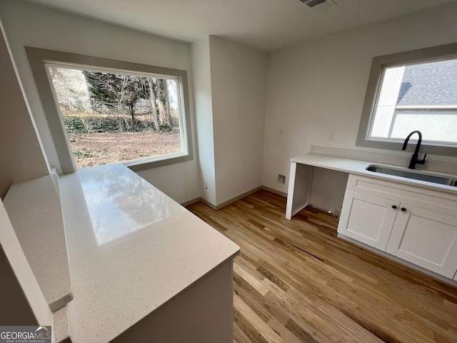 kitchen featuring white cabinetry, sink, and light hardwood / wood-style flooring