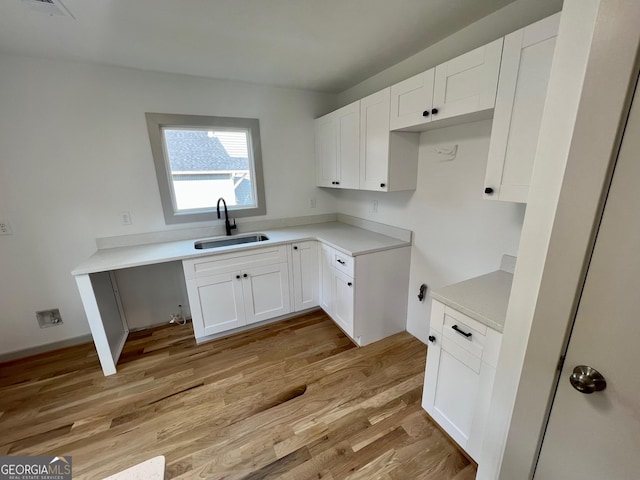 kitchen with sink, light hardwood / wood-style floors, and white cabinets