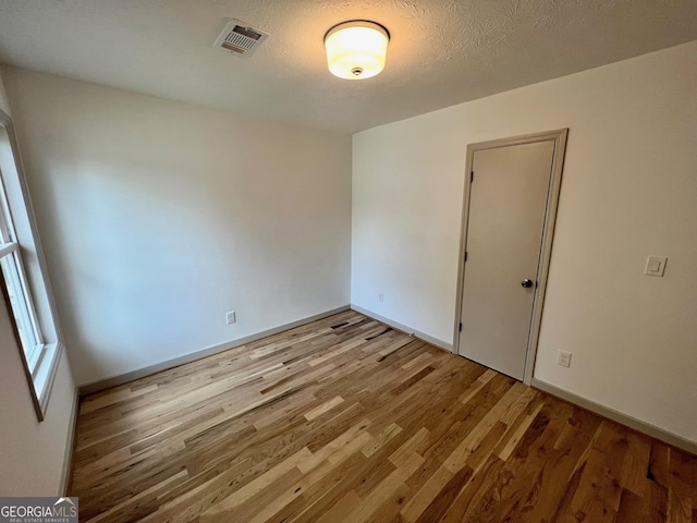 spare room with a textured ceiling and light wood-type flooring