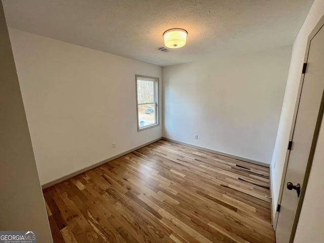 empty room with light hardwood / wood-style floors and a textured ceiling