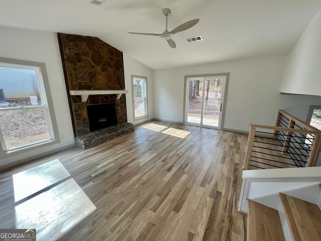 unfurnished living room with lofted ceiling, a fireplace, light hardwood / wood-style floors, and ceiling fan