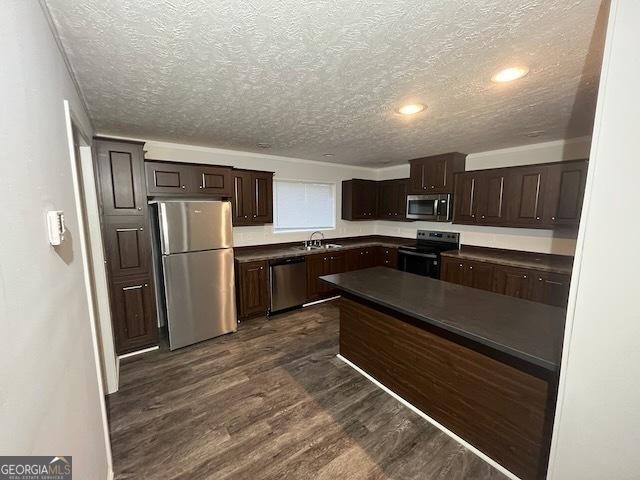 kitchen featuring stainless steel appliances, dark brown cabinets, a textured ceiling, and dark hardwood / wood-style flooring