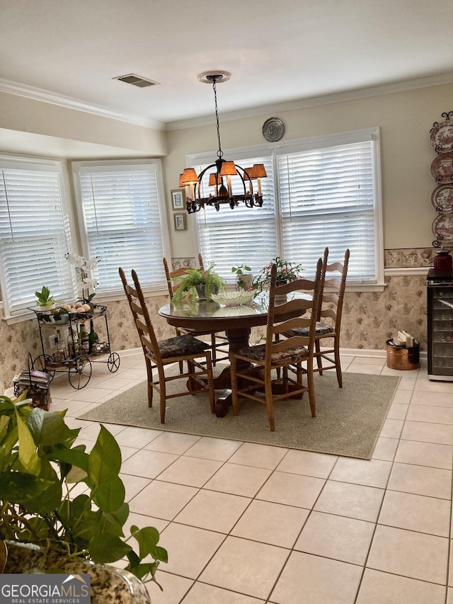 dining area with a healthy amount of sunlight, ornamental molding, a notable chandelier, and light tile patterned floors