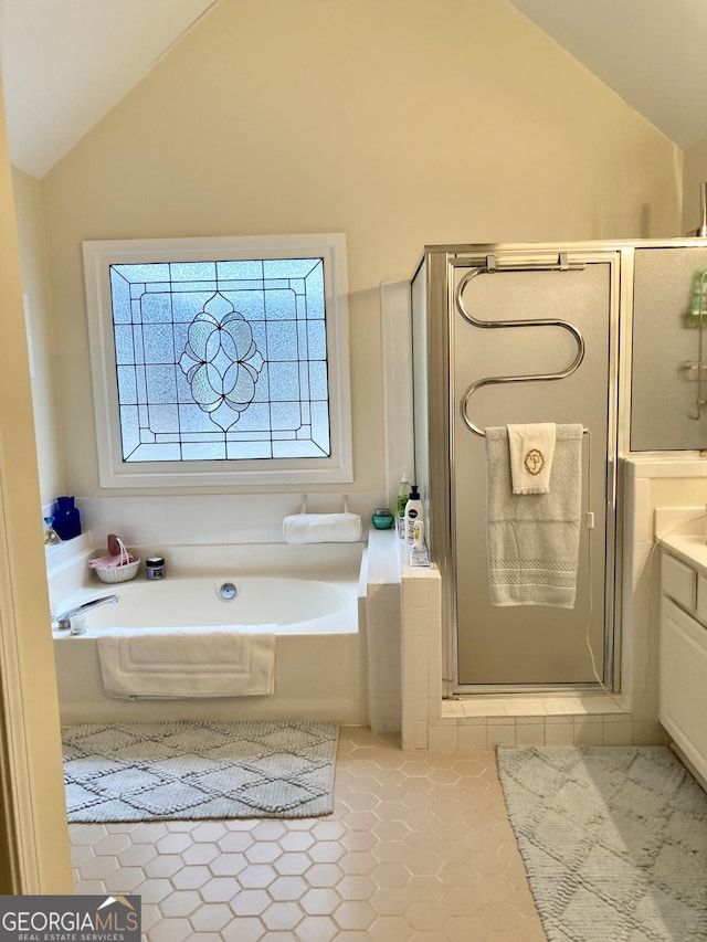 bathroom featuring tile patterned flooring, vaulted ceiling, independent shower and bath, and vanity