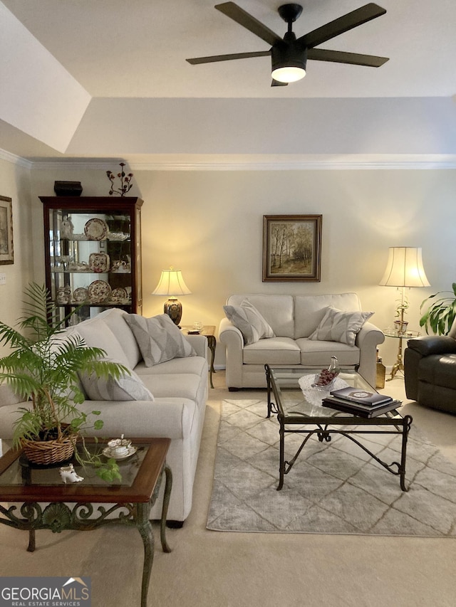 living room with a raised ceiling, crown molding, light carpet, and ceiling fan