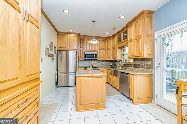 kitchen featuring pendant lighting, appliances with stainless steel finishes, light stone counters, a healthy amount of sunlight, and a kitchen island