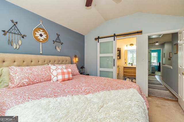 bedroom featuring connected bathroom, lofted ceiling, carpet floors, ceiling fan, and a barn door