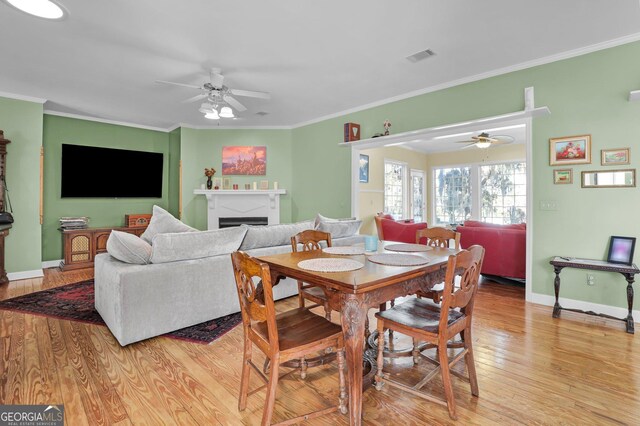 64 Lake No No Rd, Midway, GA 31320 - dining space featuring ceiling fan, light wood-type flooring, a fireplace, and crown molding