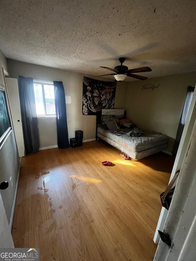 unfurnished bedroom featuring ceiling fan, hardwood / wood-style flooring, and a textured ceiling