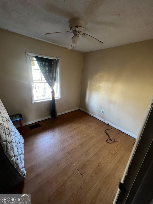 interior space with ceiling fan, wood-type flooring, and a textured ceiling