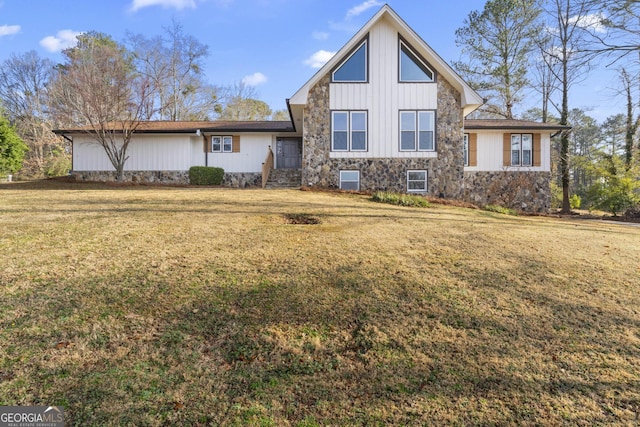 view of front of property featuring stone siding, board and batten siding, and a front yard