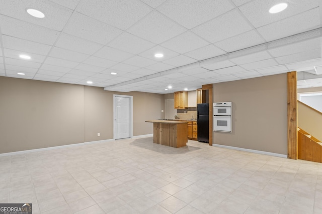 interior space featuring double oven, a paneled ceiling, and black fridge