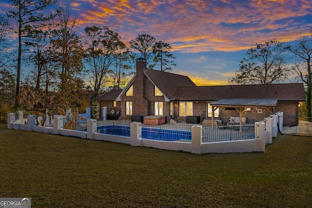 pool at dusk with a yard, outdoor lounge area, and a patio