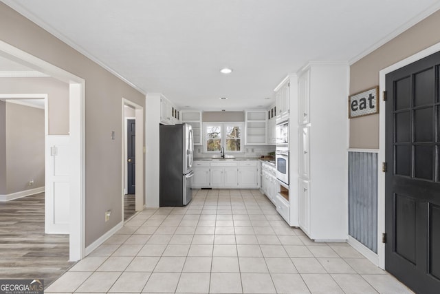 kitchen with white cabinetry, sink, ornamental molding, and appliances with stainless steel finishes