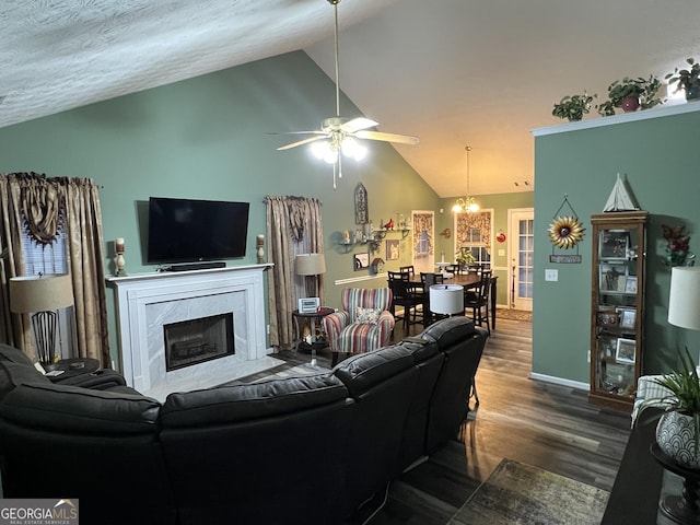 living room with vaulted ceiling, a textured ceiling, hardwood / wood-style flooring, a premium fireplace, and ceiling fan with notable chandelier