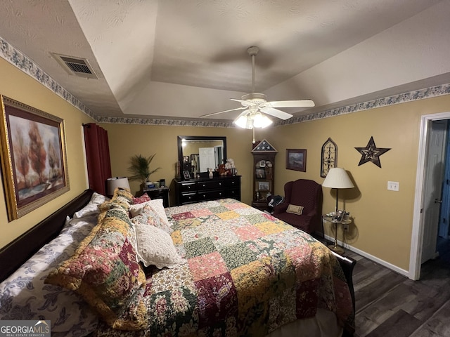 bedroom featuring a raised ceiling, dark wood-type flooring, and ceiling fan