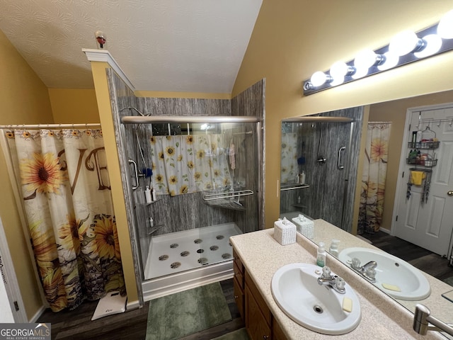 bathroom featuring walk in shower, lofted ceiling, wood-type flooring, a textured ceiling, and vanity