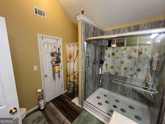 bathroom featuring lofted ceiling, hardwood / wood-style flooring, a textured ceiling, and walk in shower