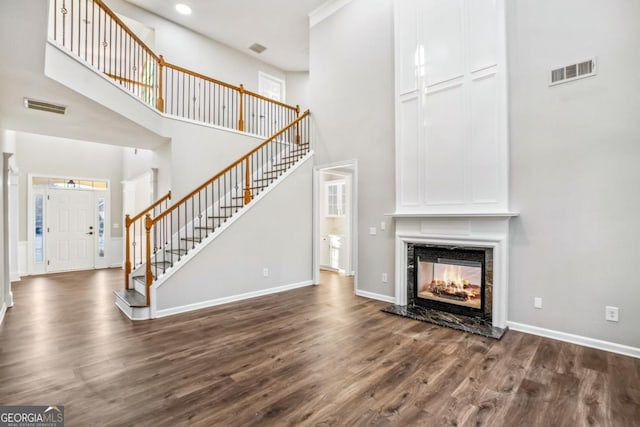 unfurnished living room with dark wood-type flooring, stairway, visible vents, and a premium fireplace