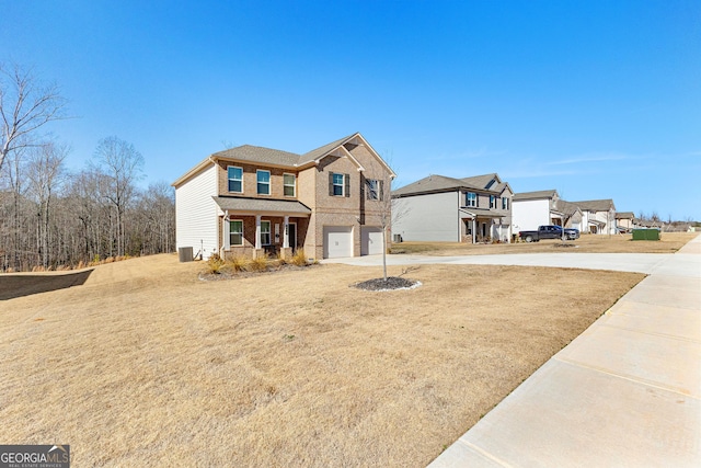 view of front of house with a garage, a front yard, central AC, and covered porch