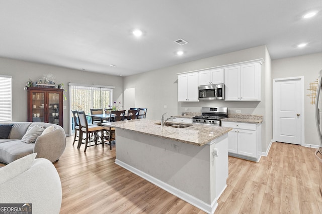 kitchen with stainless steel appliances, sink, a center island with sink, and white cabinets