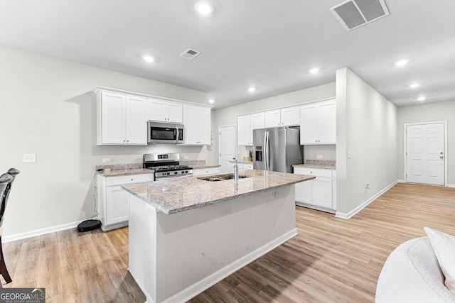 kitchen with an island with sink, appliances with stainless steel finishes, sink, and white cabinets