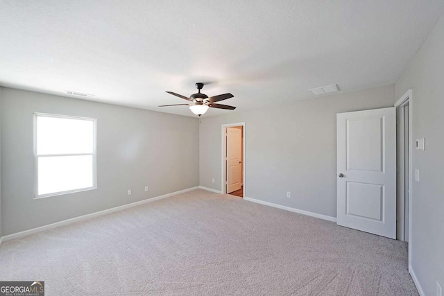 spare room with ceiling fan and light colored carpet