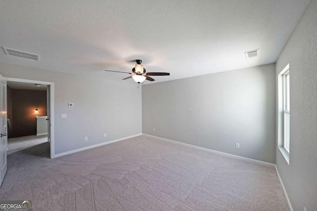 spare room featuring ceiling fan, carpet, and a textured ceiling