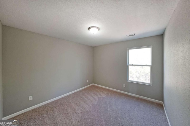 carpeted empty room featuring a textured ceiling