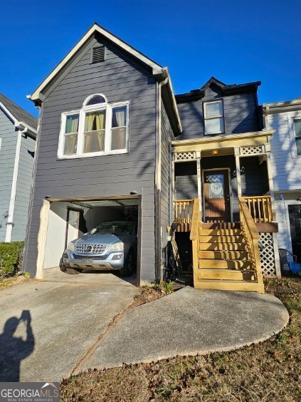 view of front of home with concrete driveway, covered porch, and an attached garage