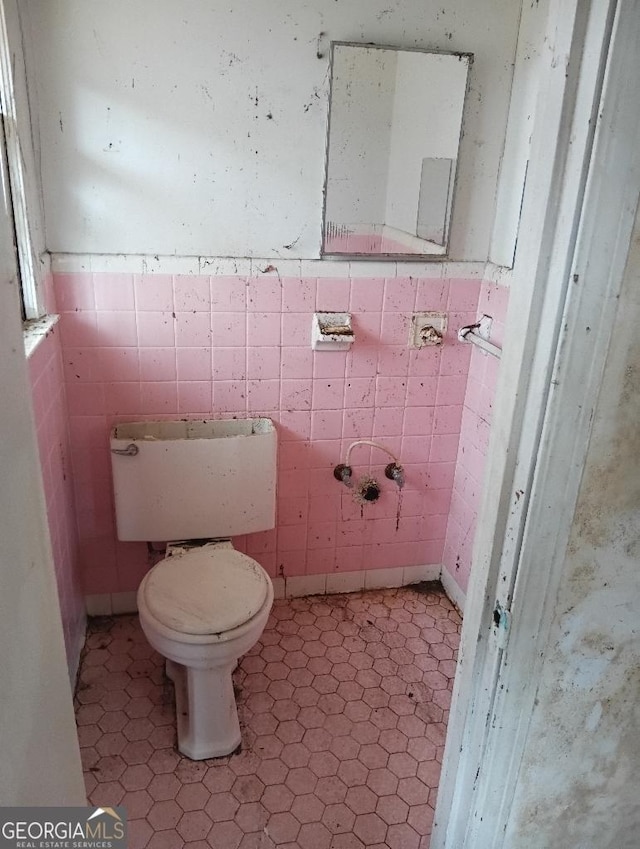 bathroom featuring tile walls and toilet