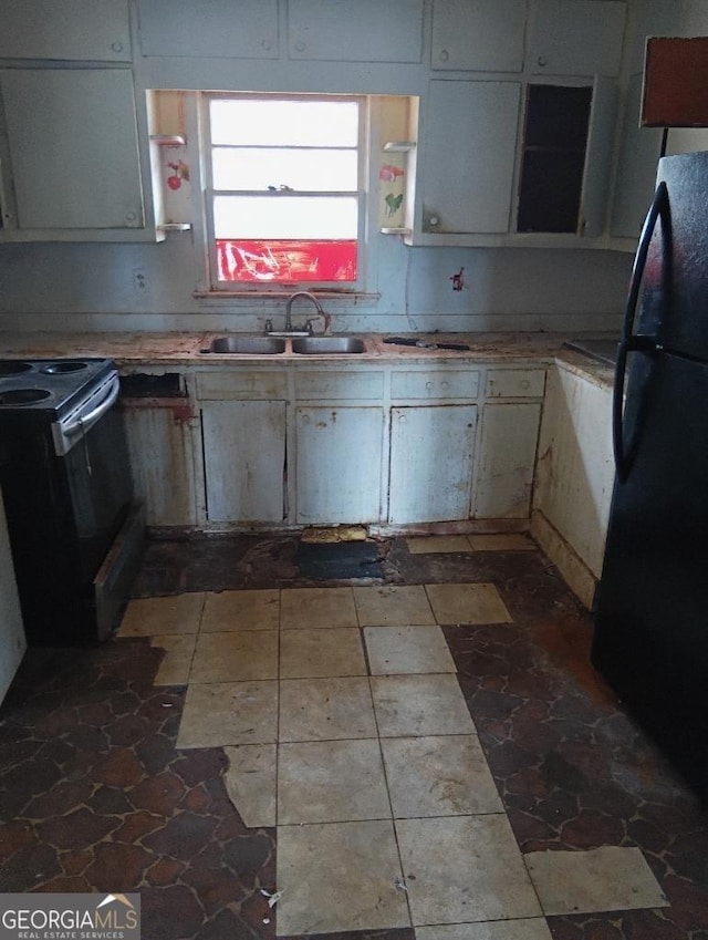 kitchen featuring black refrigerator, sink, and electric range