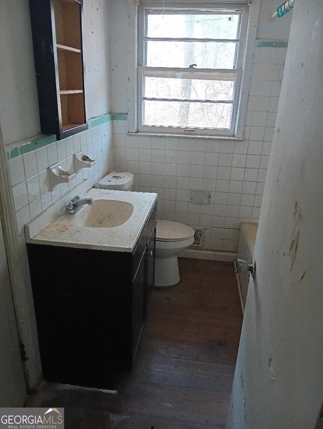 bathroom featuring vanity, toilet, wood-type flooring, and tile walls