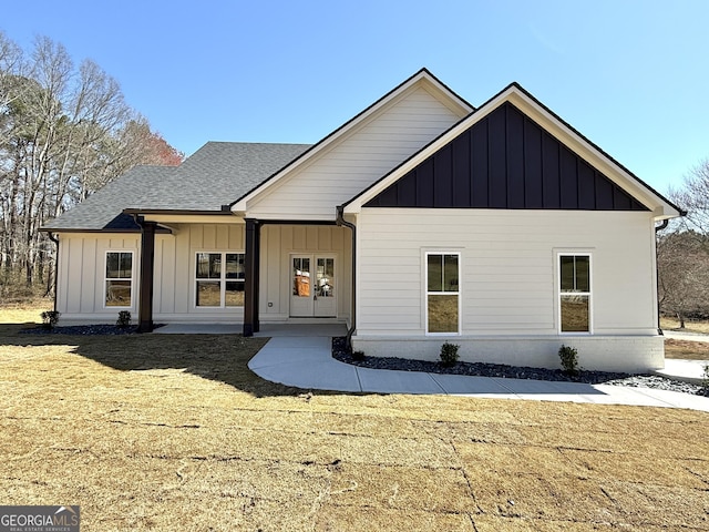 modern farmhouse style home featuring roof with shingles, board and batten siding, and a front yard