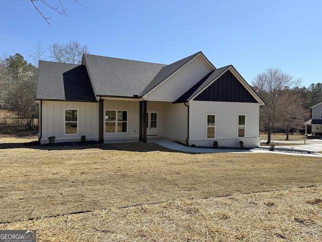 back of property featuring a lawn, board and batten siding, and roof with shingles