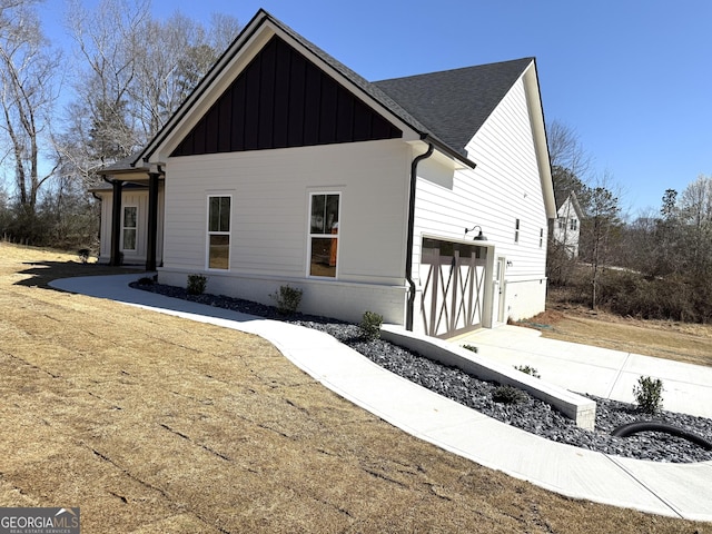 view of side of property with a garage, board and batten siding, and a shingled roof