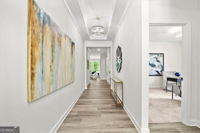 corridor featuring a notable chandelier, crown molding, and light hardwood / wood-style flooring