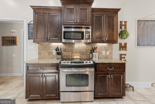 kitchen with stainless steel appliances, dark brown cabinets, light stone counters, and decorative backsplash