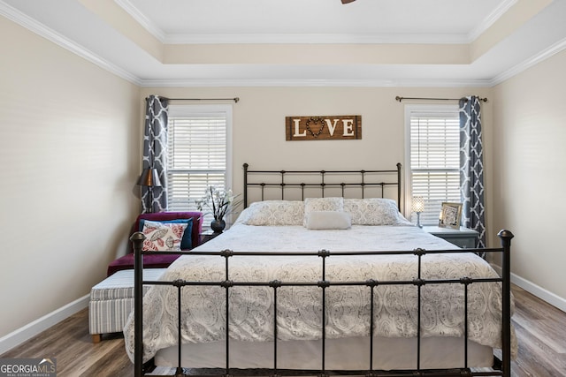 bedroom featuring hardwood / wood-style flooring, ornamental molding, and a raised ceiling