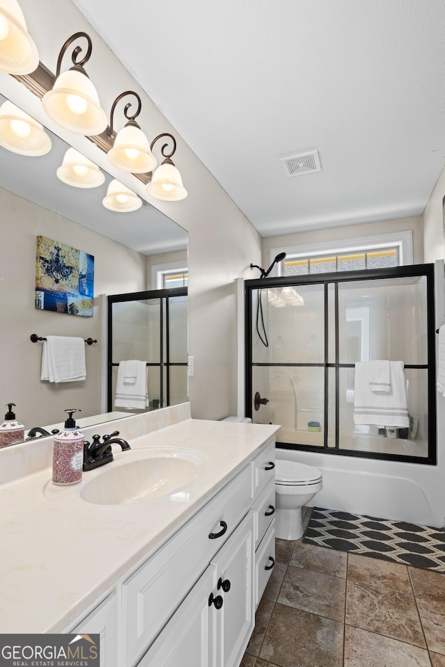 full bathroom with vanity, toilet, and bath / shower combo with glass door