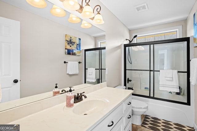 full bathroom with bath / shower combo with glass door, vanity, and toilet